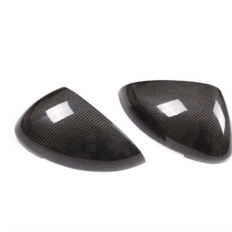 Glossy black true carbon fibre rearview mirror cover for Porsche Macan on a white background