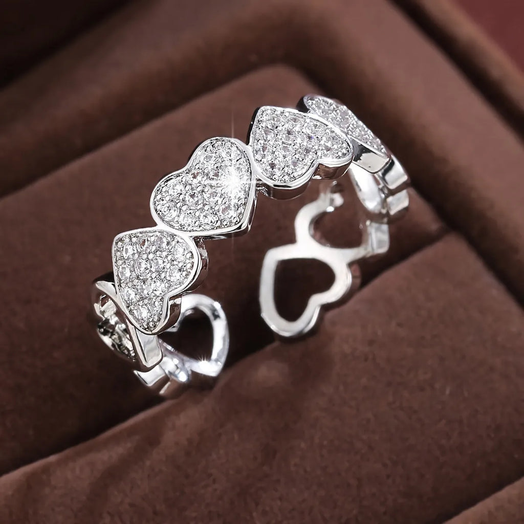 Gold copper couple ring with adjustable opening and love heart design on plain background