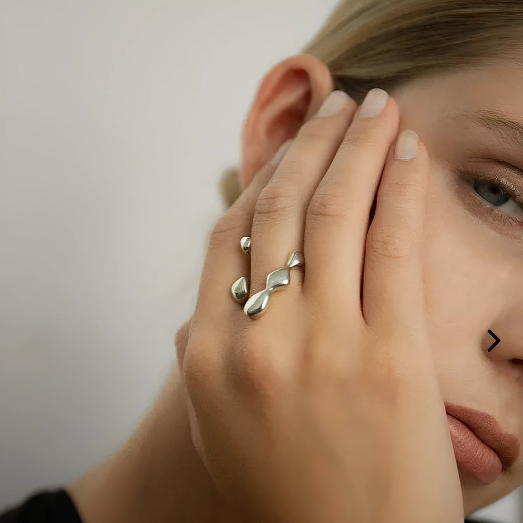 Gold or silver brass opening ring with spherical design elements on a model's finger.