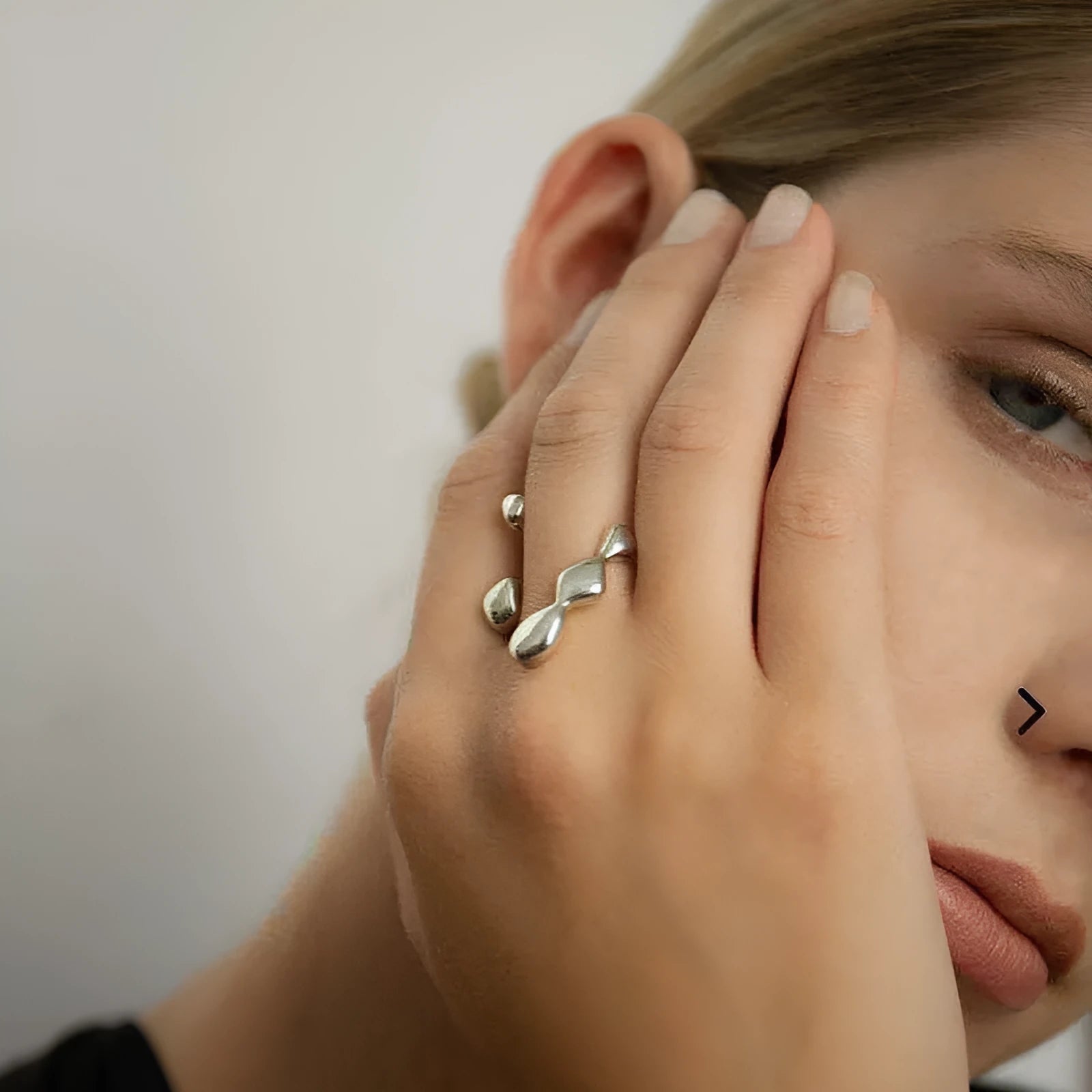 Gold or silver brass opening ring with spherical design elements on a model's finger.