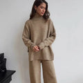 Women's dark grey knit co-ord suit with side-slit sweater and matching trousers laid flat.