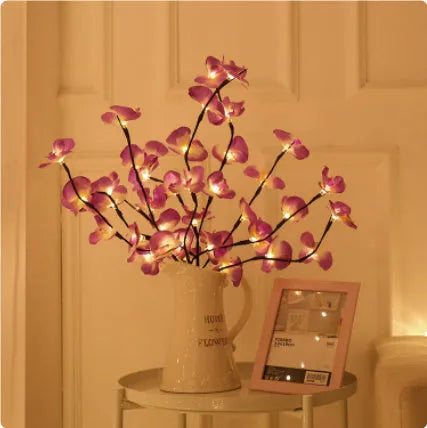 Pink LED phalaenopsis orchid branch decorative light, 65 cm tall, on a table.
