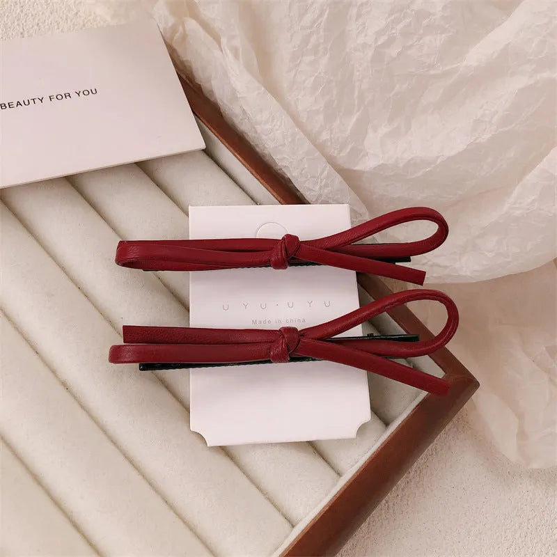 Wine red leather bow hair barrette on hair, showing single clip design