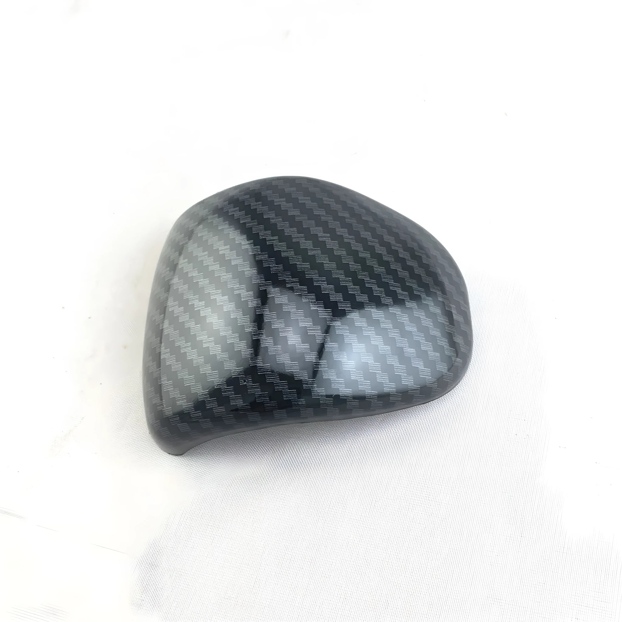 Black gear shift cover with a carbon fibre pattern for car interior styling.