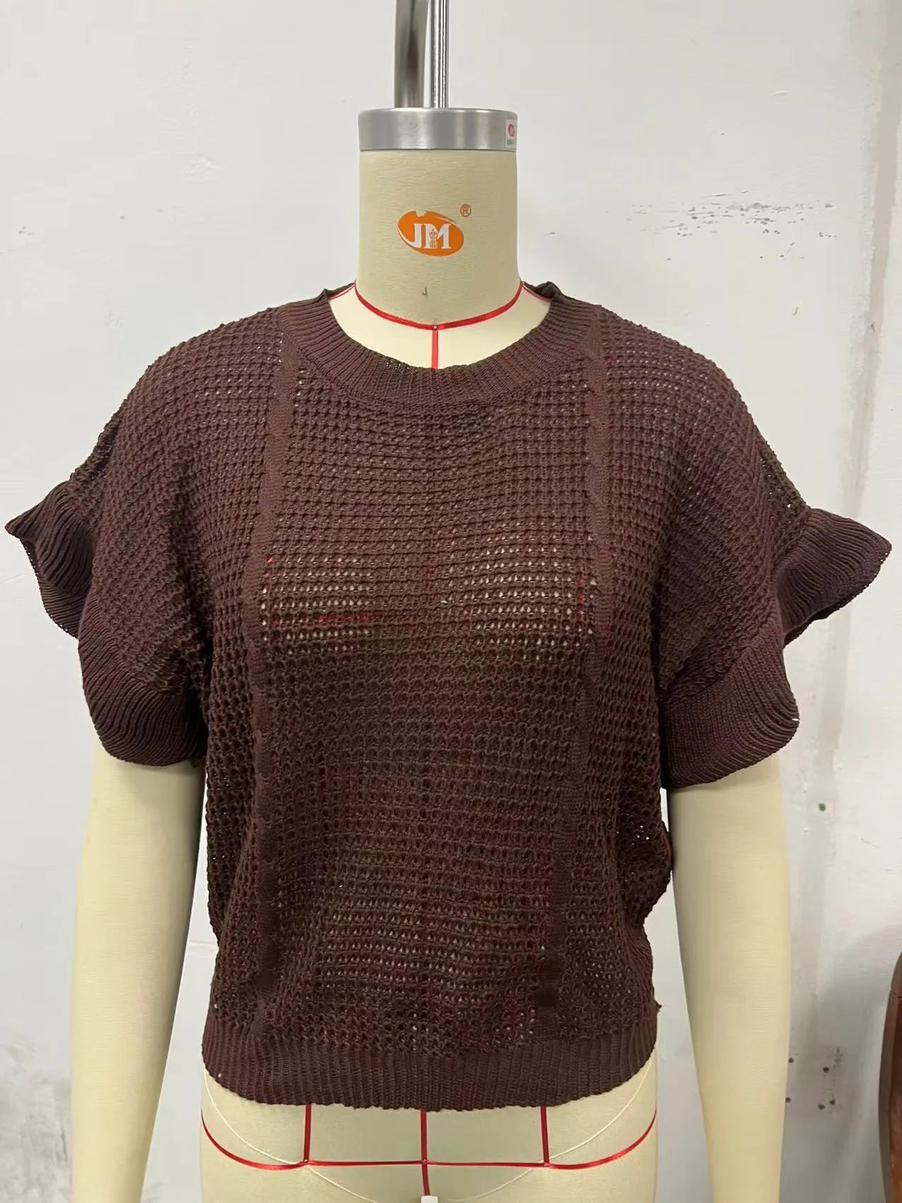 White knitted pullover sweater with 3D twisted string pattern and ruffled short sleeves on a hanger.