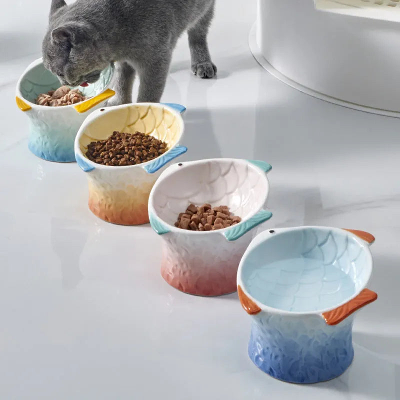 Blue ceramic fish-shaped cat bowl with tilted design and shallow eating surface on a plain background.