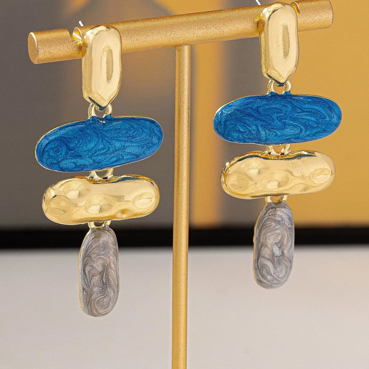 A pair of simple geometric stud earrings with a multicolour metallic finish.