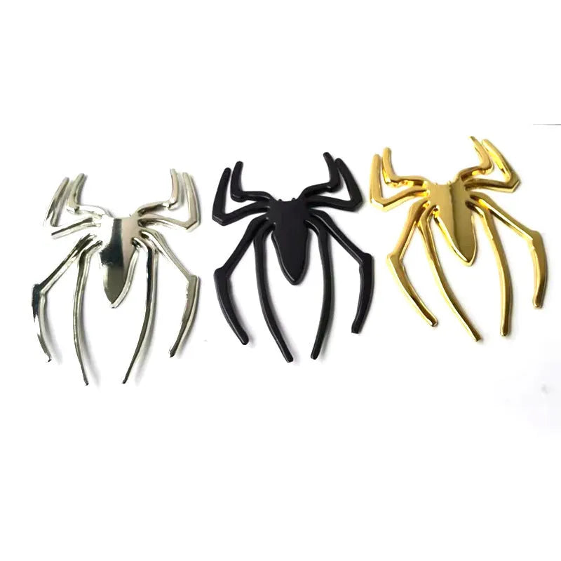 Three-dimensional metal spider-shaped bumper sticker in silver finish on a white background.