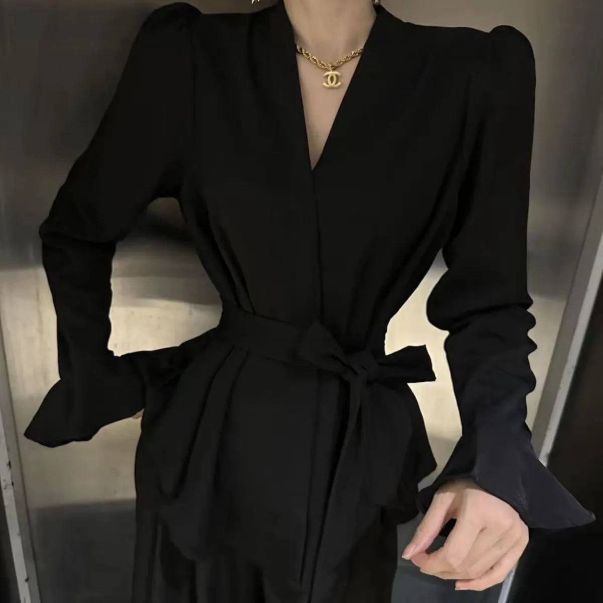 Woman wearing a wine red long sleeve shirt with an irregular French collar, bell sleeves, and a tie front.