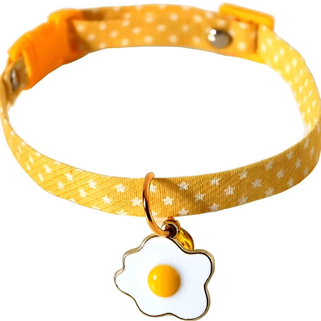 Green adjustable cat collar with a metal bell and a pink bow tie attached, shown on a measuring tape indicating size