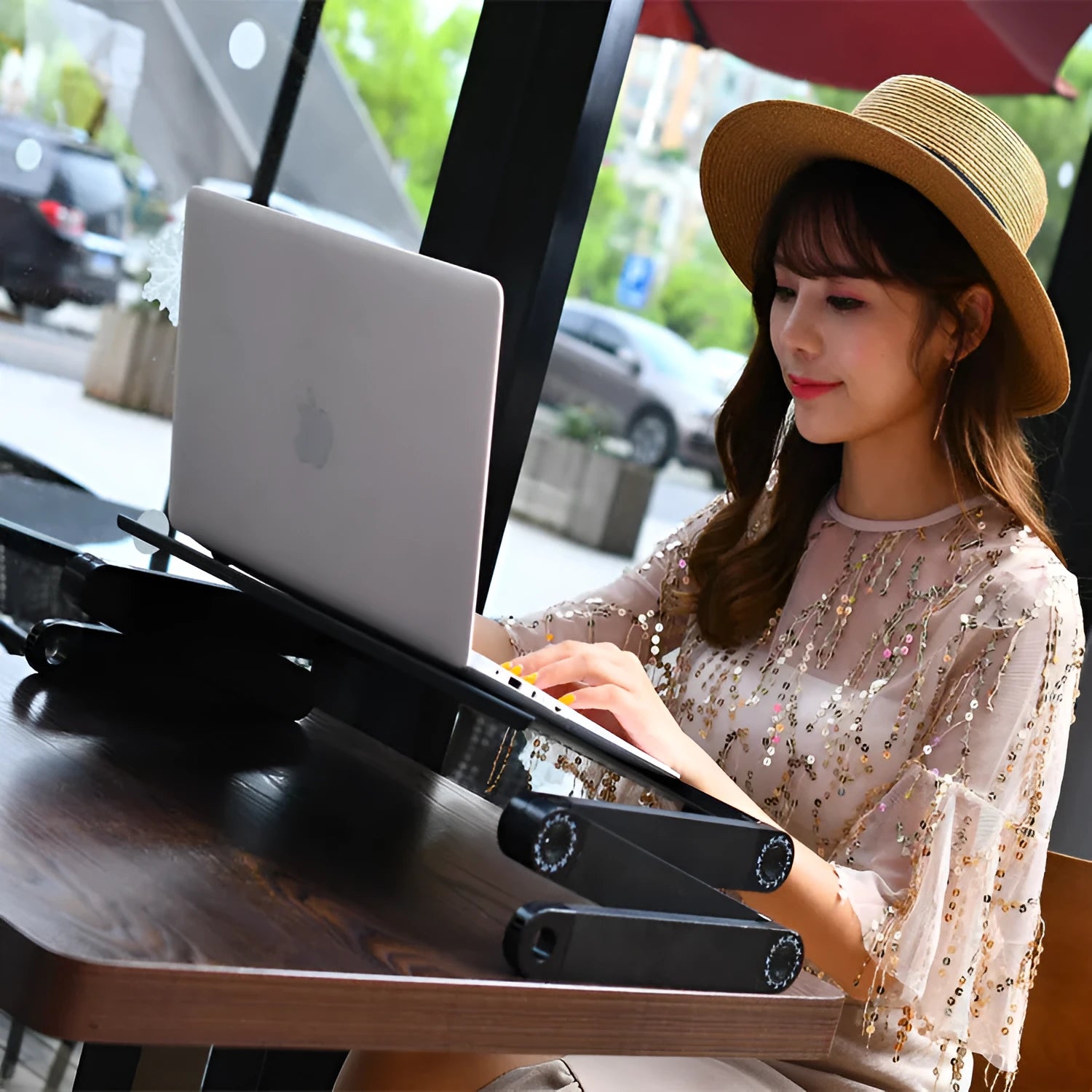 Black folding metal laptop bed table with cooling fans extended over a sofa