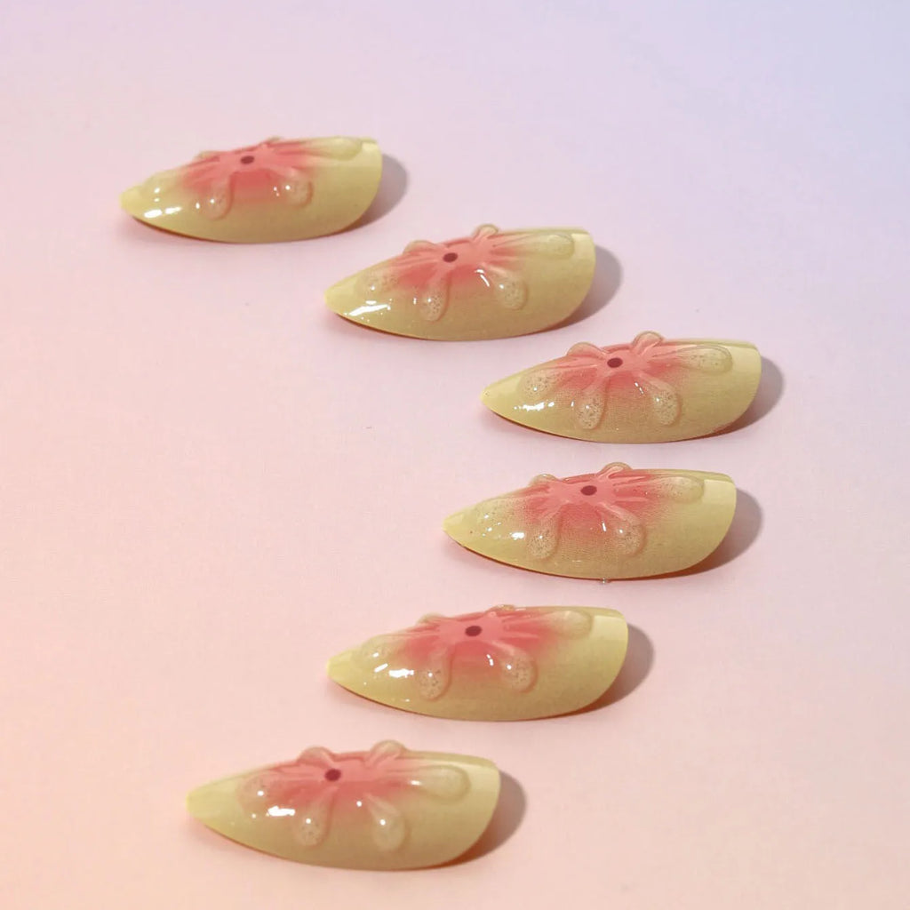 Set of plastic detachable fake nails with pink and white 3D cartoon flower designs, pot of jelly glue, and a nail file.