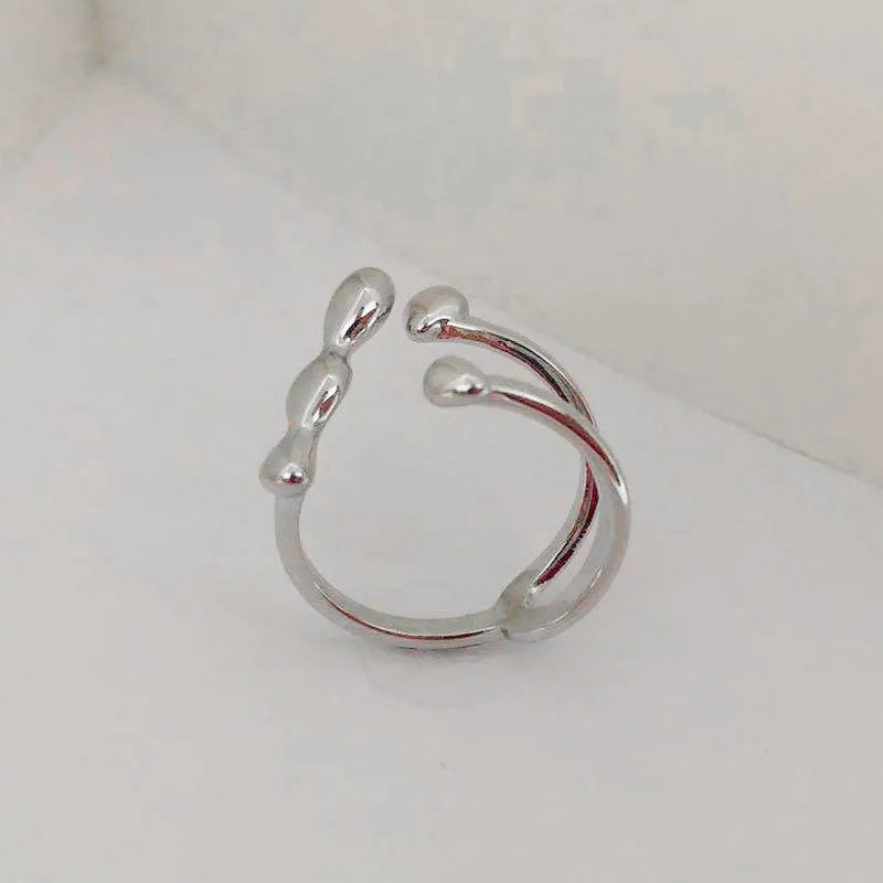 Gold or silver brass opening ring with spherical design elements on a model's finger.