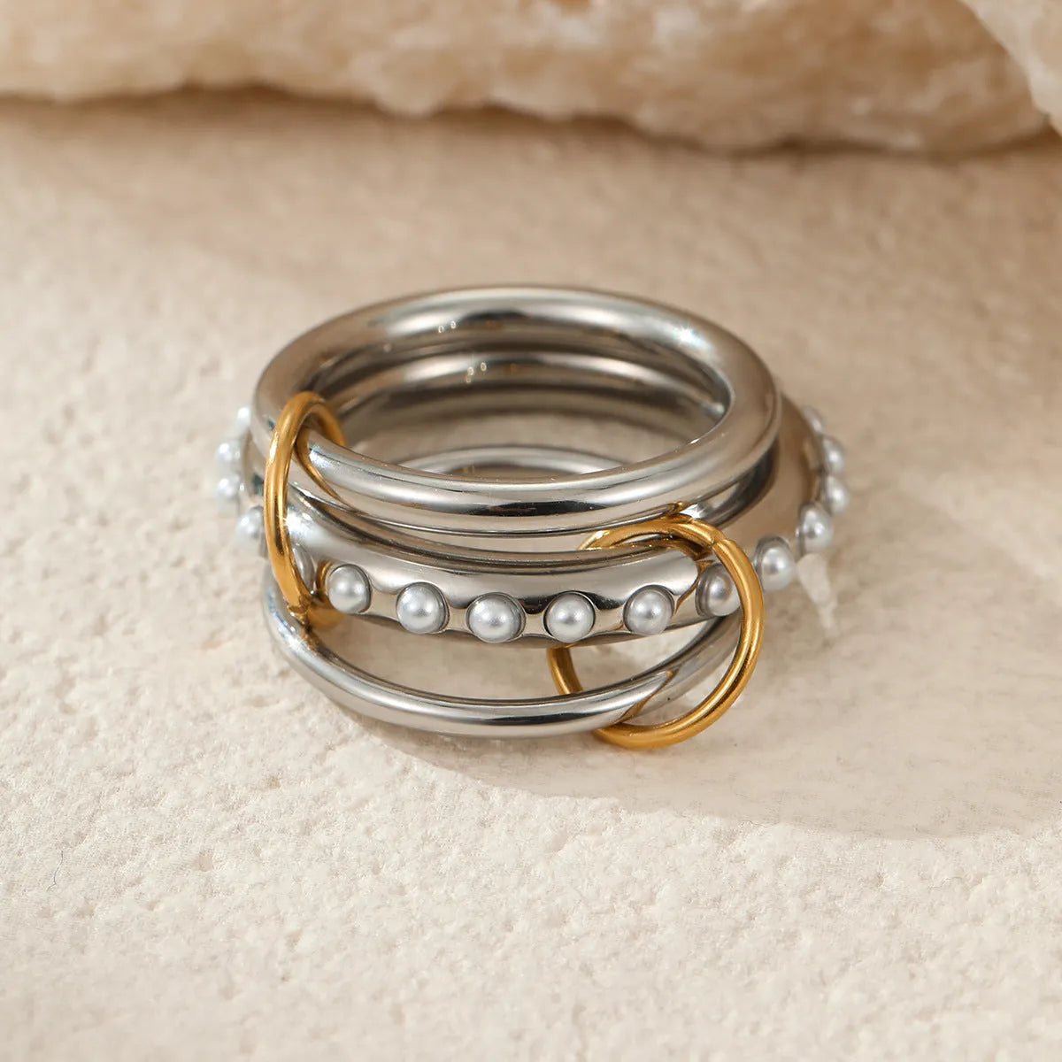 Stacked gold plated stainless steel ring set showing exaggerated design on a model's hand.
