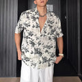 Man wearing a loose black floral print short sleeve casual shirt with a cardigan style open front.