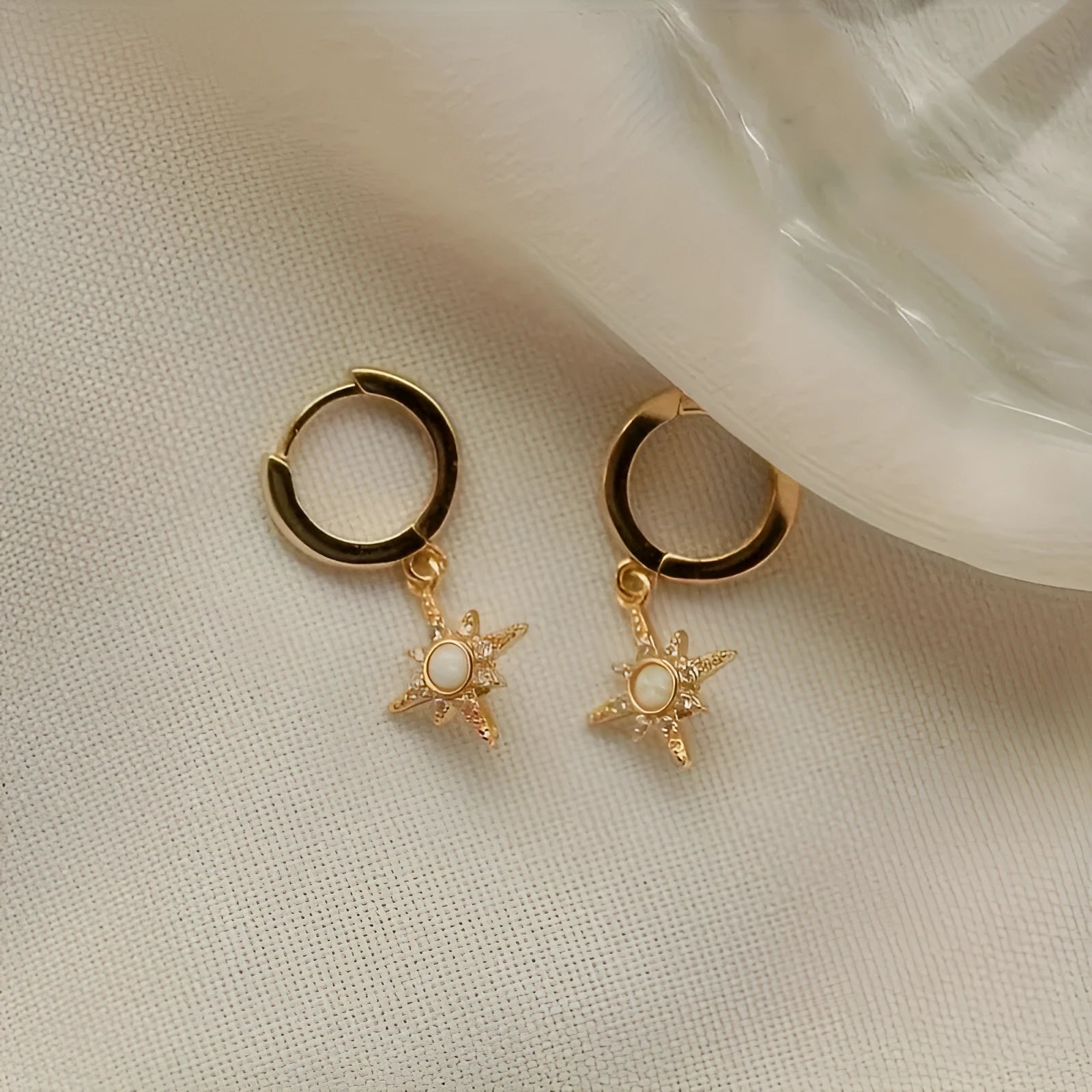 Gold copper eight-pointed star opal stud earrings on a white background