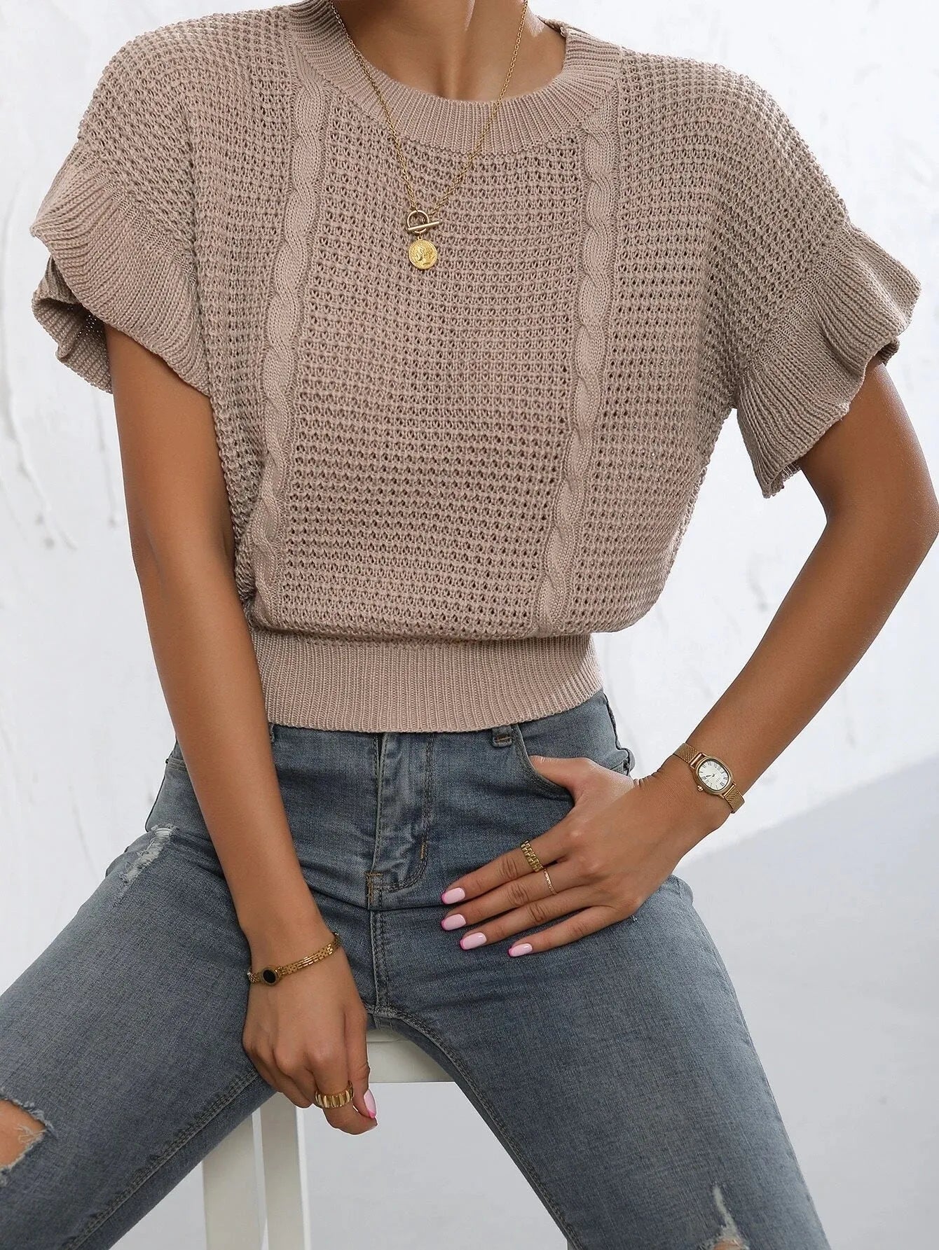 White knitted pullover sweater with 3D twisted string pattern and ruffled short sleeves on a hanger.