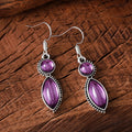 A pair of black and purple vintage geometric pendant earrings with bohemian style on a white background.