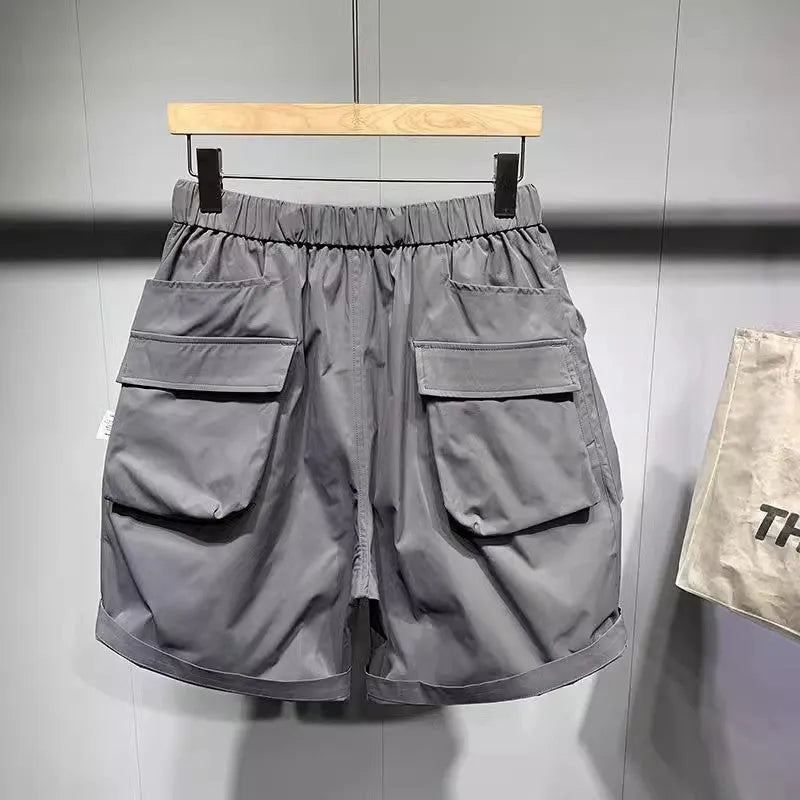 Man wearing loose fit black workwear shorts with pockets, showing above-the-knee length and straight leg style.