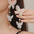White butterfly-shaped earrings with tassels, pearls, rhinestones, and lace details on electroplated copper alloy