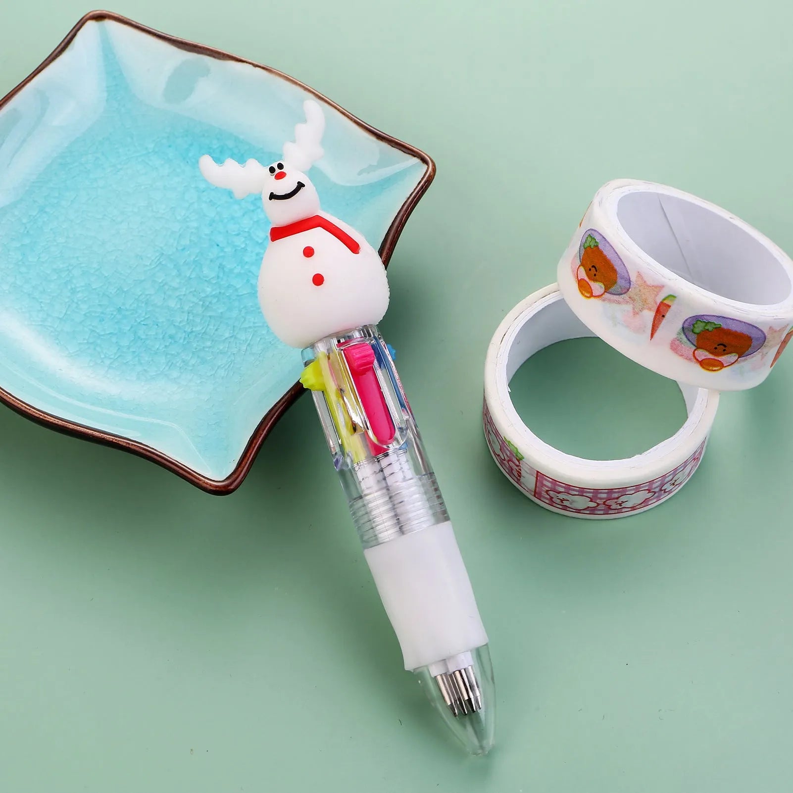 Christmas-themed ballpoint pen with press button, showing designs of snowmen, reindeer, and trees on plastic barrel.