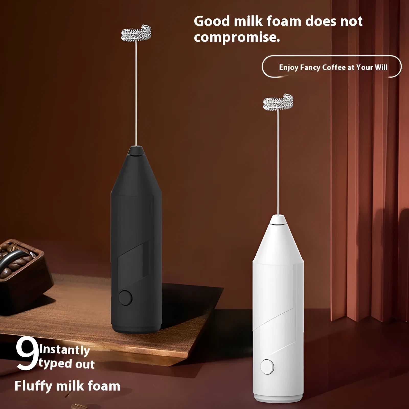 Compact black handheld USB rechargeable milk frother with stainless steel whisk on a kitchen counter.