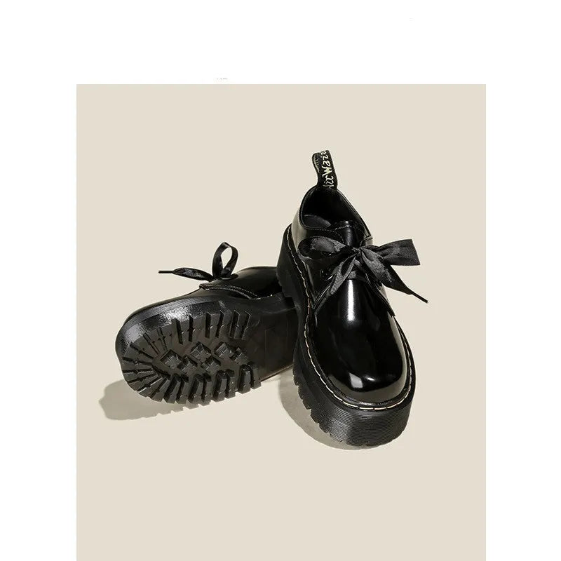 Women's black thick soled lace-up shoes with ribbon detail on a white background