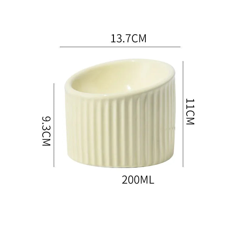 Dark green elevated ceramic cat bowl on a wooden floor, showing its raised height and round, whisker-friendly shape.