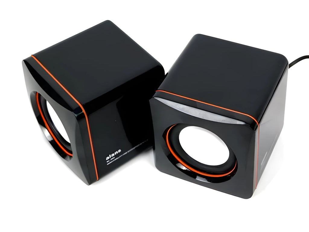 Black square USB computer speaker on desktop next to monitor