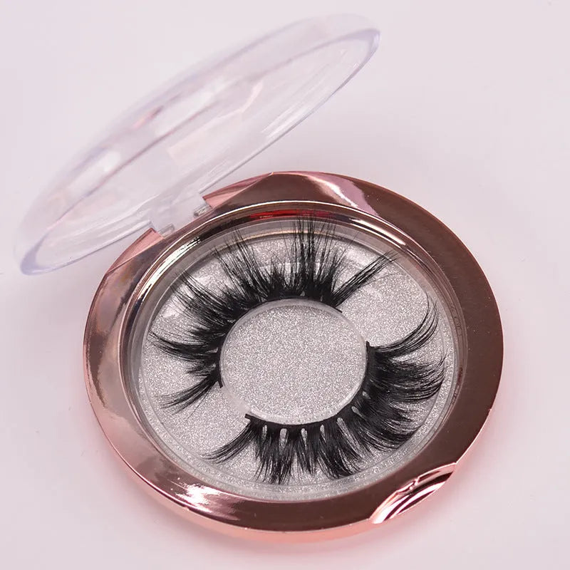 A pair of 5D style false eyelashes made from mink hair, shown with a double-headed brush and a black hair cap.