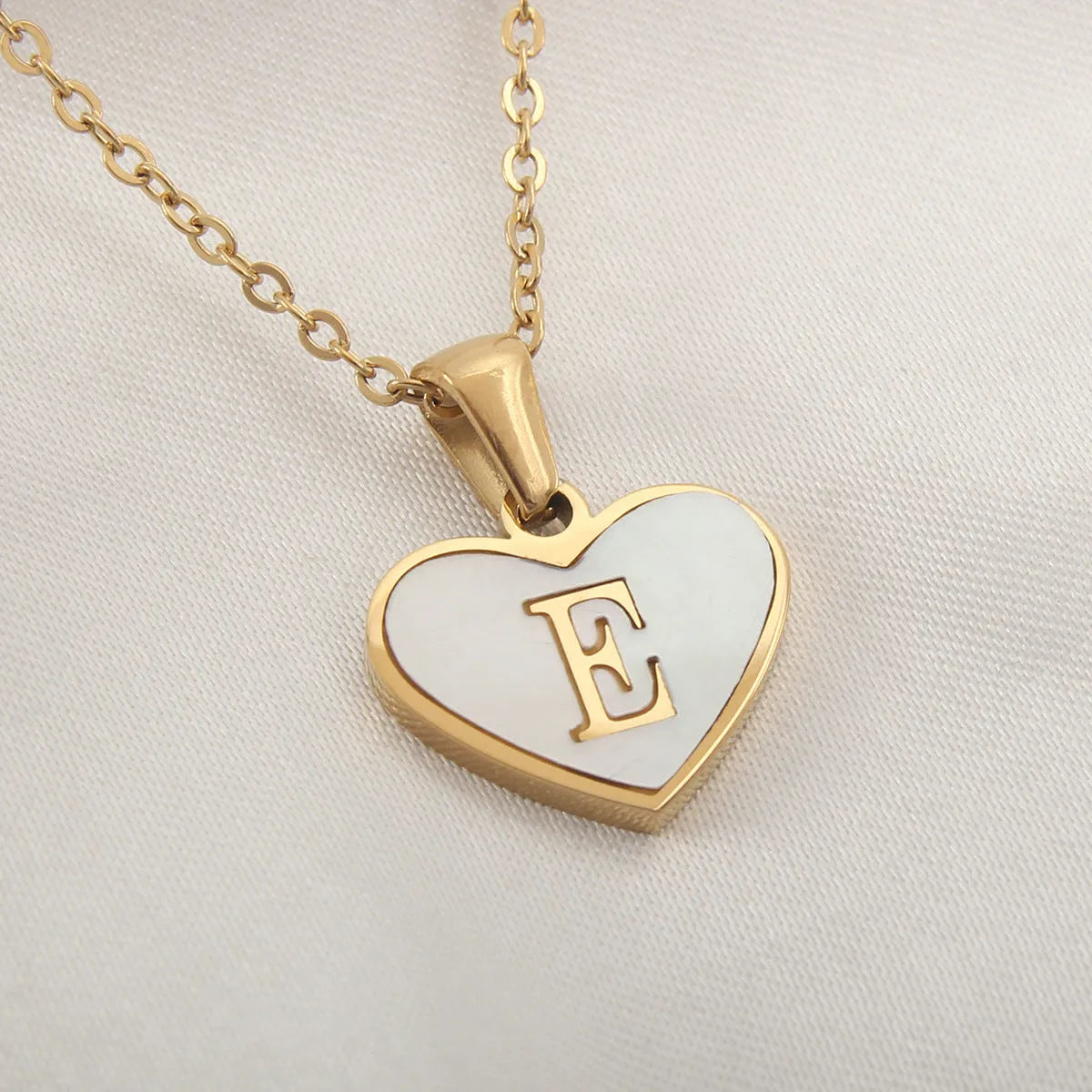 Gold-plated heart necklace with white shell pendant personalised with a letter, on an adjustable chain.