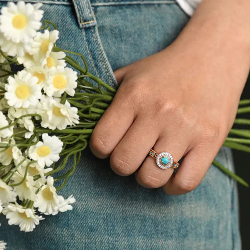 Close-up of a women's rose gold turquoise ring with geometric inlaid zircon stones on a copper band.