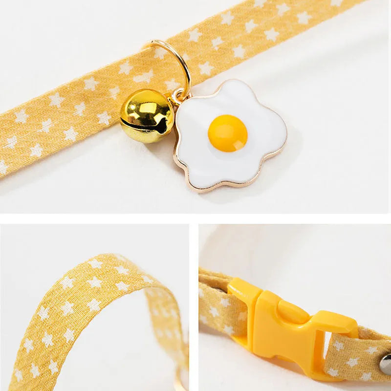 Green adjustable cat collar with a metal bell and a pink bow tie attached, shown on a measuring tape indicating size