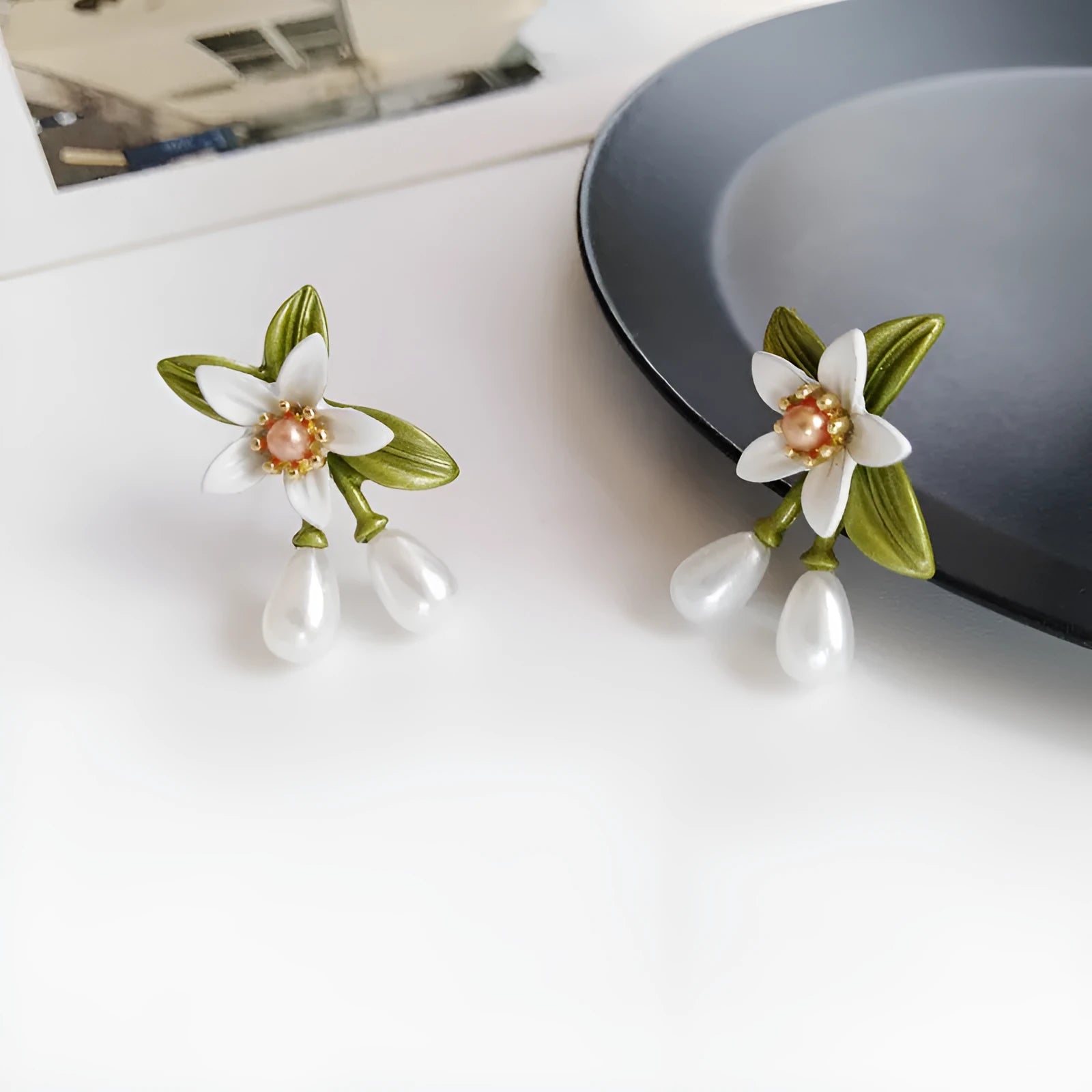 A pair of women's earrings showing sterling silver camellia flower studs and a matching alloy flower clip on a white background.