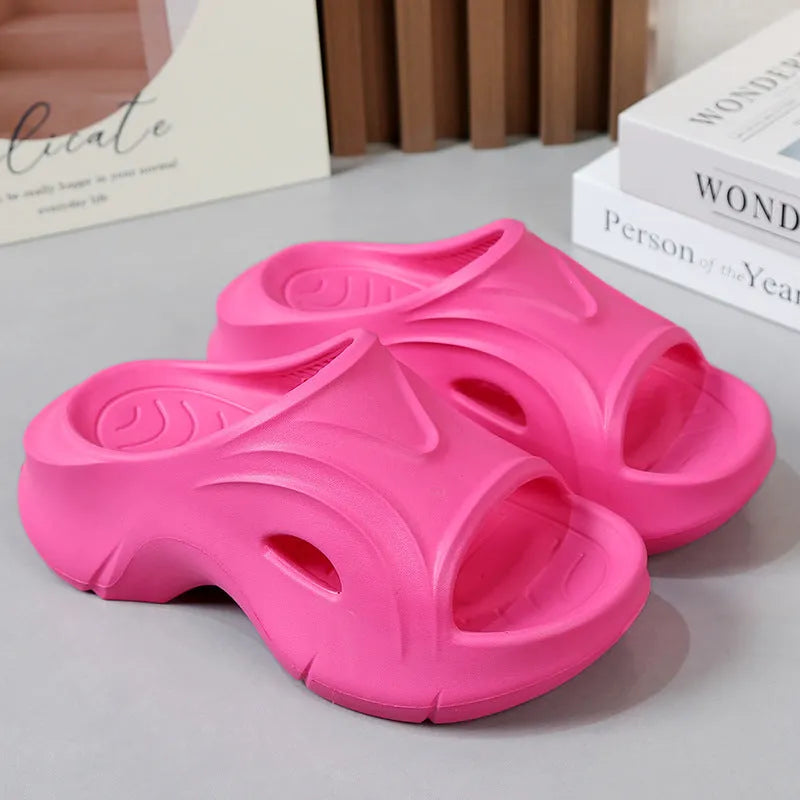 Women's thick-soled EVA slippers in rose red, shown on a beach background.