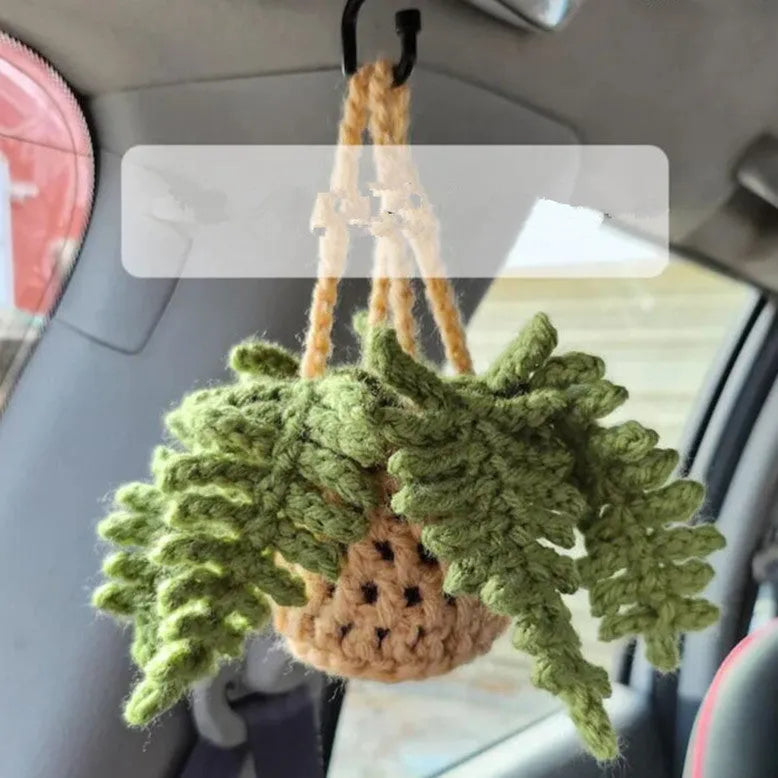 Green and white knitted wool car plant decoration with hanging rope on car dashboard