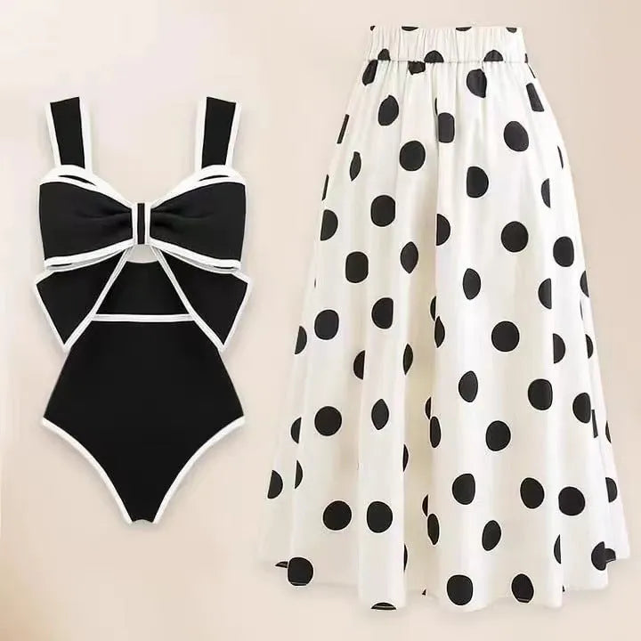 Women's black one-piece swimsuit with a white bow-accented beach dress cover-up skirt.