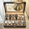 Grey leather watch storage box with clear lid showing watch compartments
