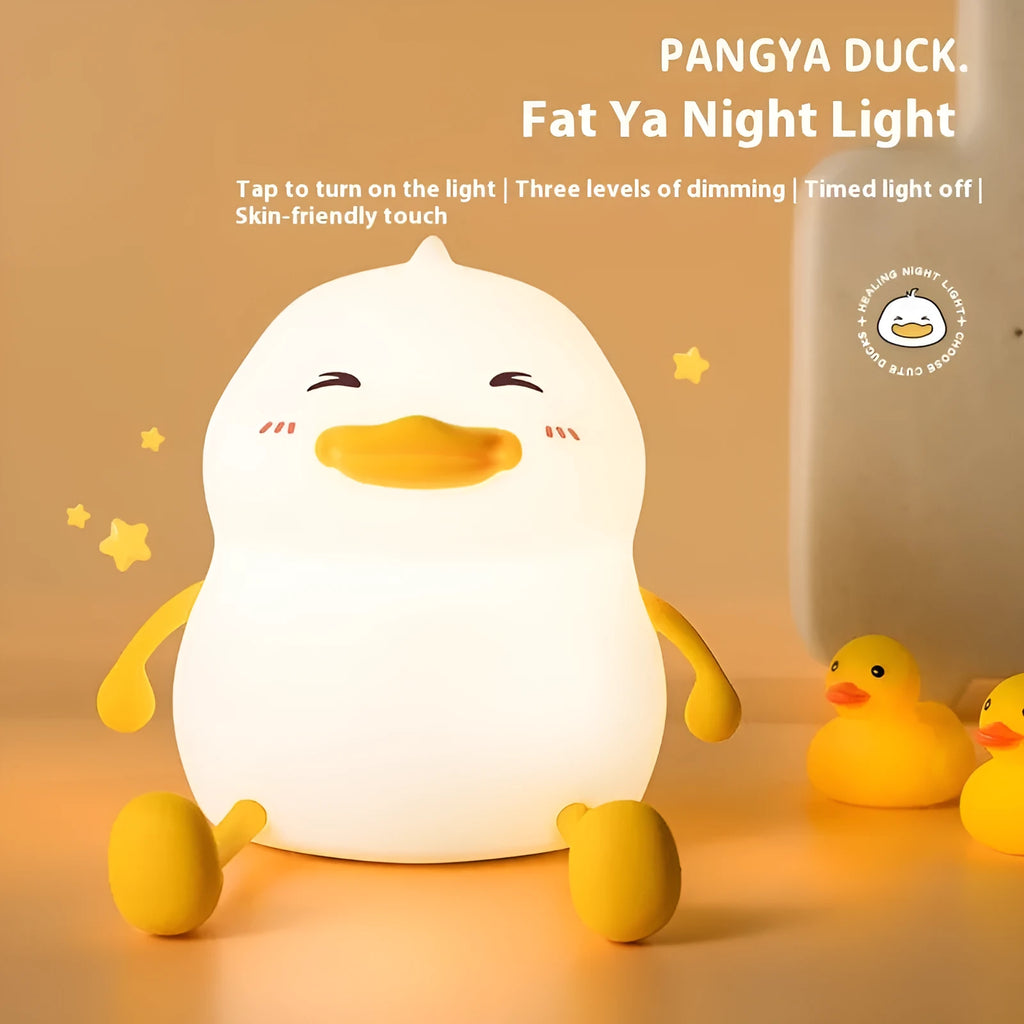 Chubby silicone pat night light on a desk holding a mobile phone, showing its compact size and soft design.
