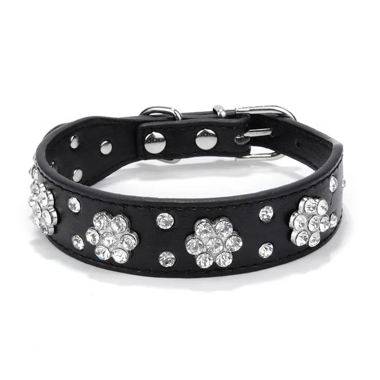 Close-up of a pink PU leather dog collar with silver rhinestone flowers and studs, showing the metal D-ring.