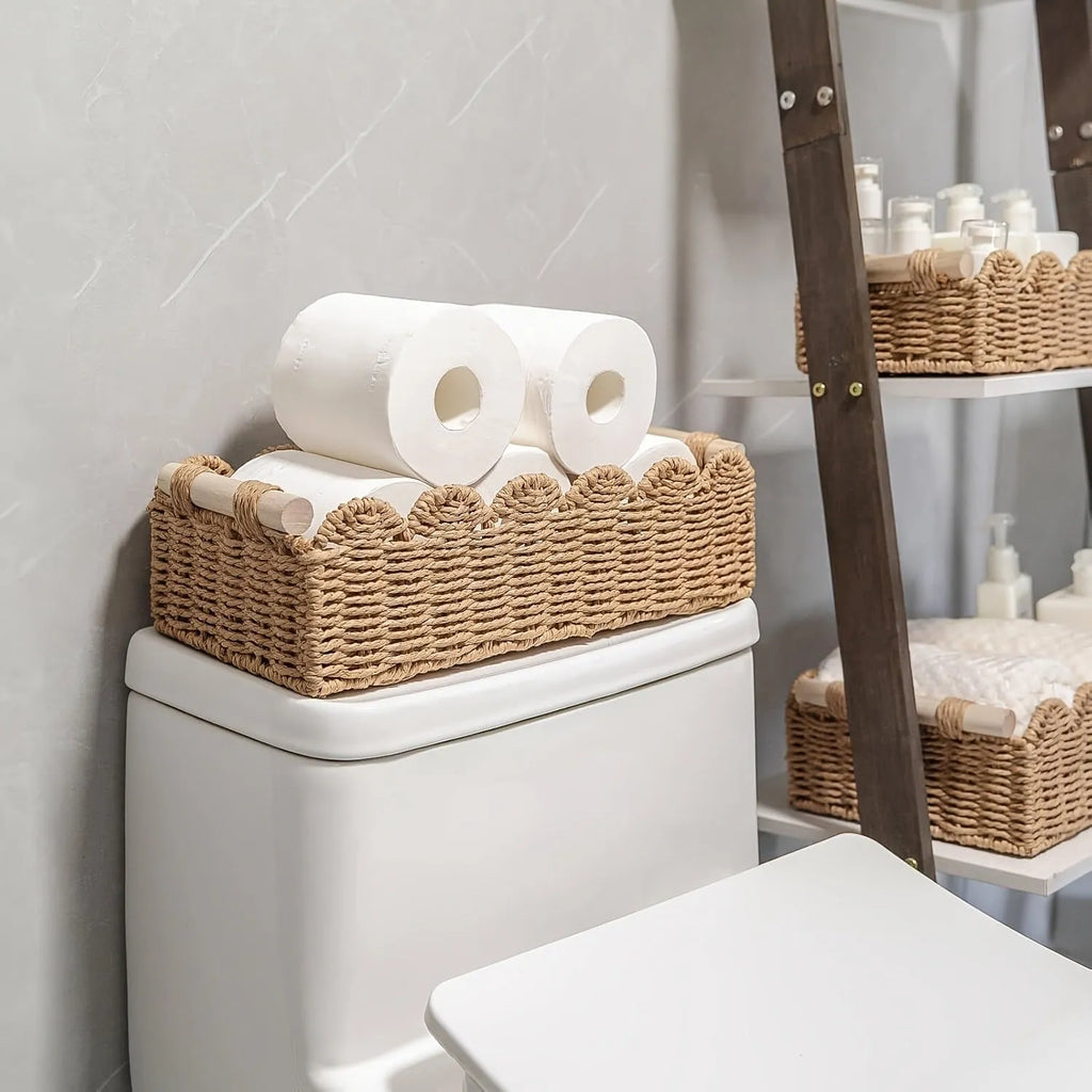 Woven paper storage basket in khaki colour on a desktop, holding remote controls and stationery.