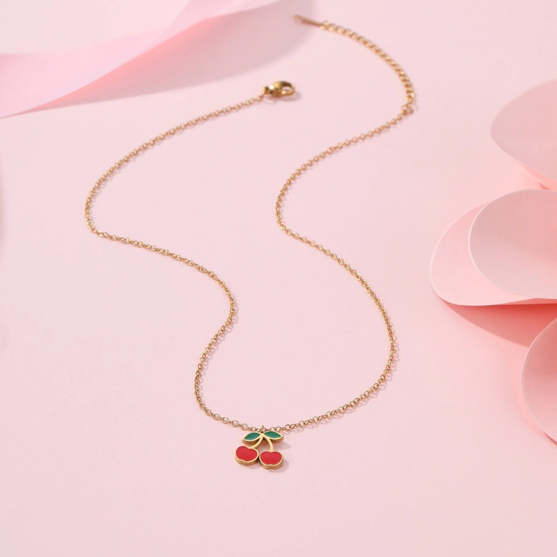Cherry-themed jewellery set showing stainless steel necklace, bracelet, earrings, and ring with 18K gold plating.