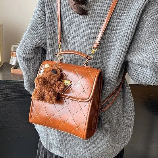 PU mini backpack in brown with stitching detail and pendant, front view