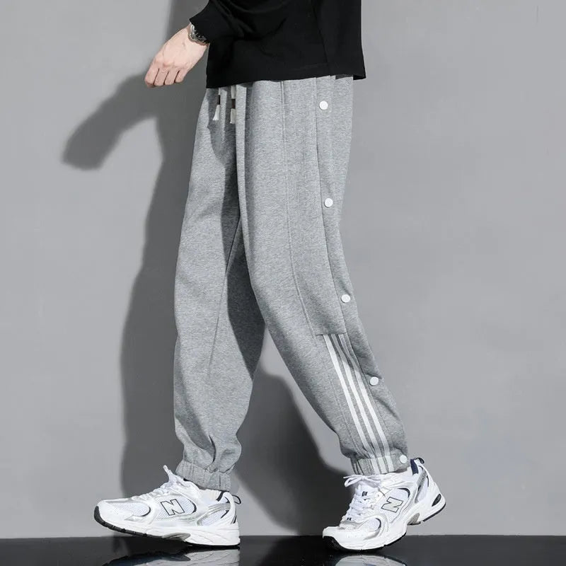 Man wearing loose grey cotton blend sweatpants with ankle ties and a drawstring waist.
