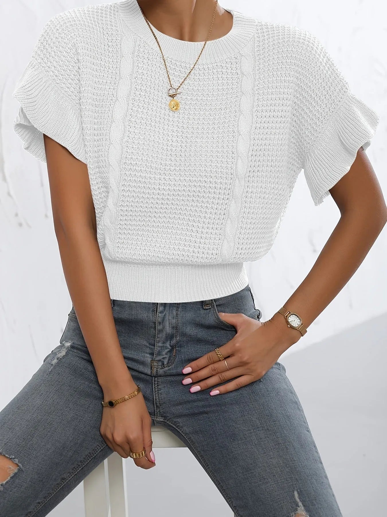 White knitted pullover sweater with 3D twisted string pattern and ruffled short sleeves on a hanger.