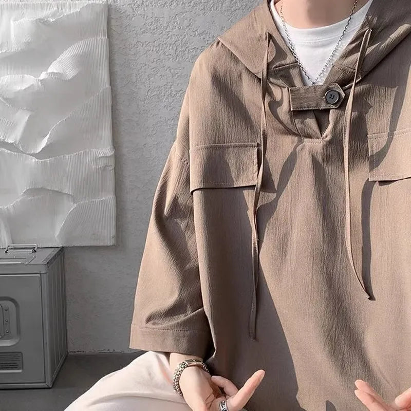Man modelling a loose grey hooded short sleeve t-shirt, showing the pullover style and front design.