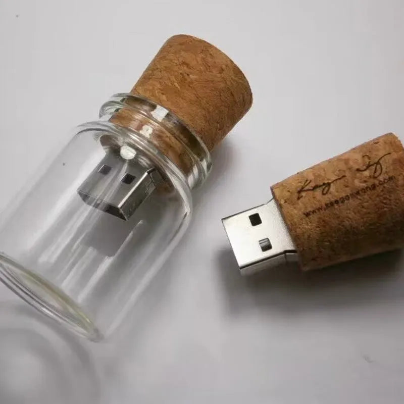 Wooden-capped transparent glass bottle USB flash drive on a wooden surface.