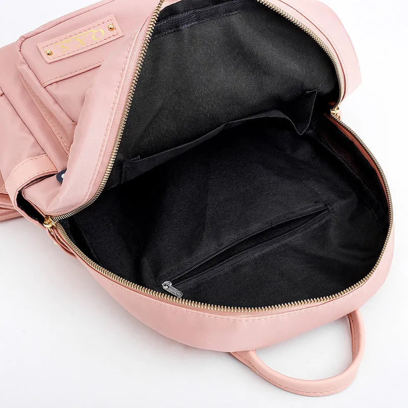 Black nylon casual travel backpack with double shoulder straps, external pockets, and a soft handle on a solid background.