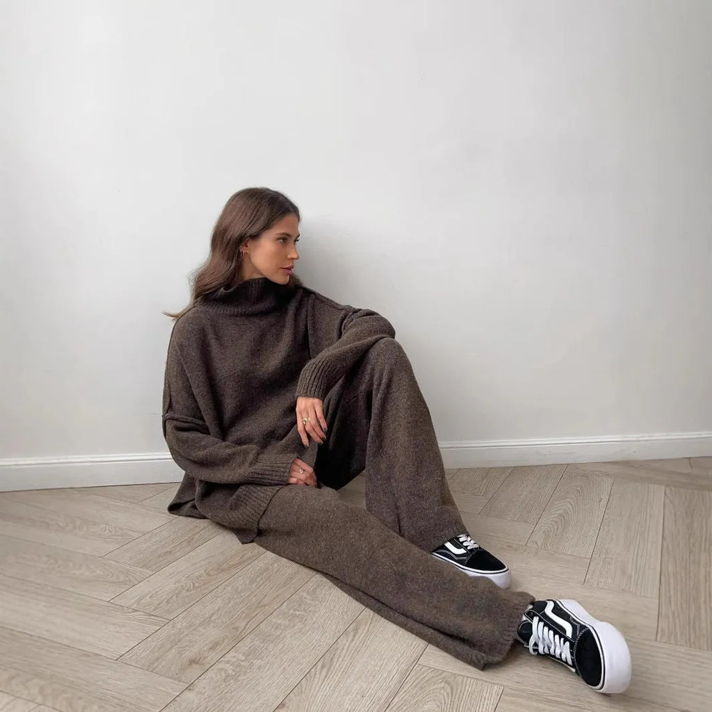 Women's dark grey knit co-ord suit with side-slit sweater and matching trousers laid flat.
