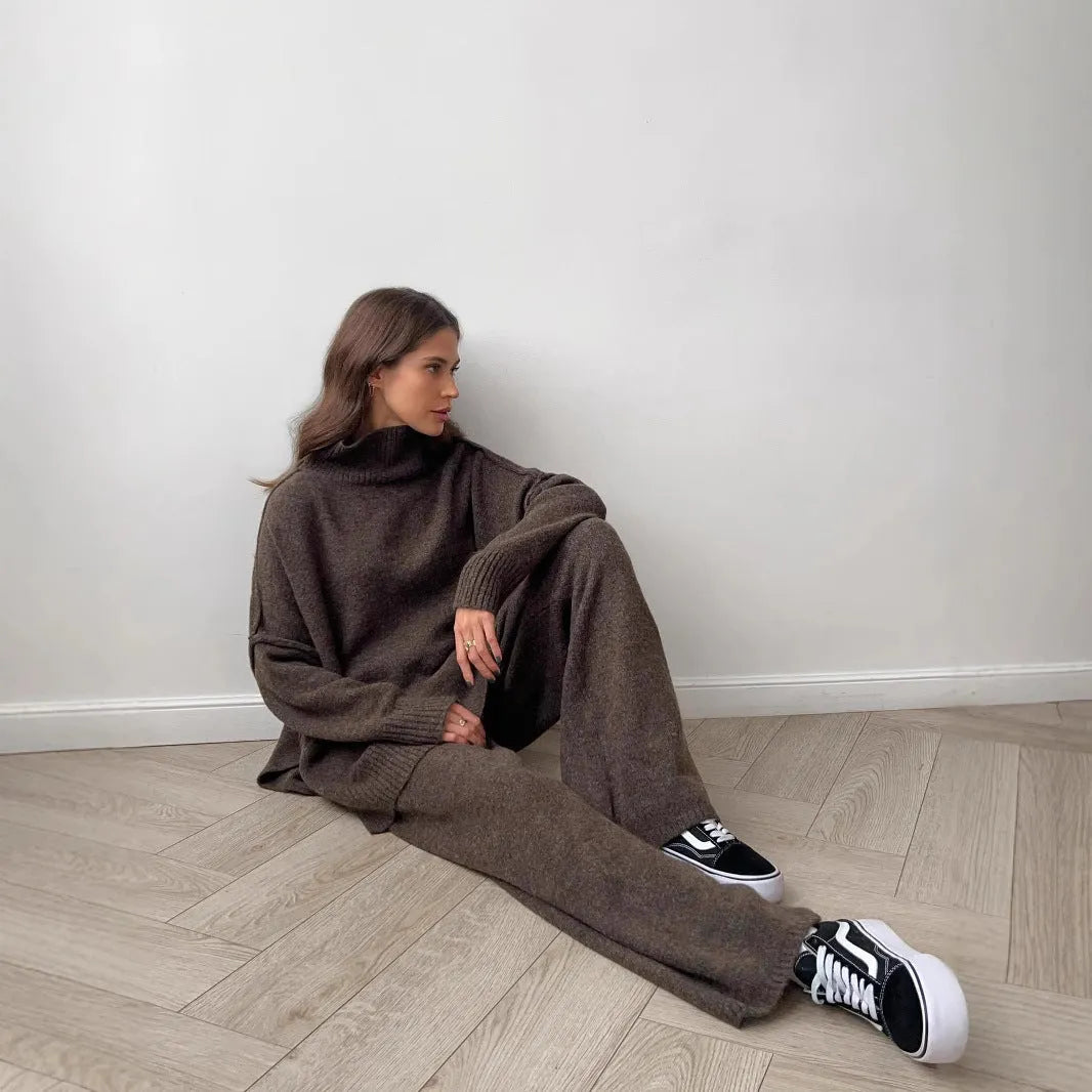 Women's dark grey knit co-ord suit with side-slit sweater and matching trousers laid flat.